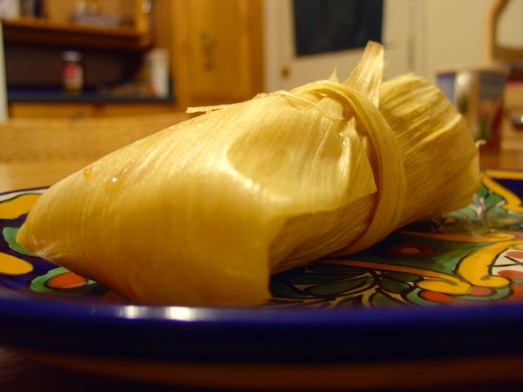 Tamale, still wrapped in corn husk.